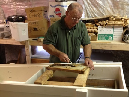 A Four B’s Farm beekeeper uncapping a honey frame